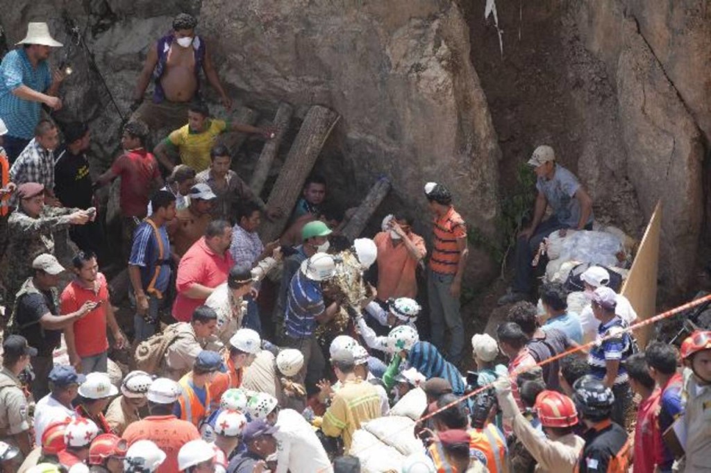 TG500. SAN JUAN ARRIBA (HONDURAS), 04/07/2014.- Mineros hondureños y la Cruz Verde salvadoreña rescatan hoy, viernes 4 de julio de 2014, a tres de once mineros que se encuentran soterrados desde el miércoles 2 de julio al derrumbarse una mina artesanal en donde trabajaban en la comunidad de San Juan Arriba en el sur de Honduras. EFE/Gustavo Amador