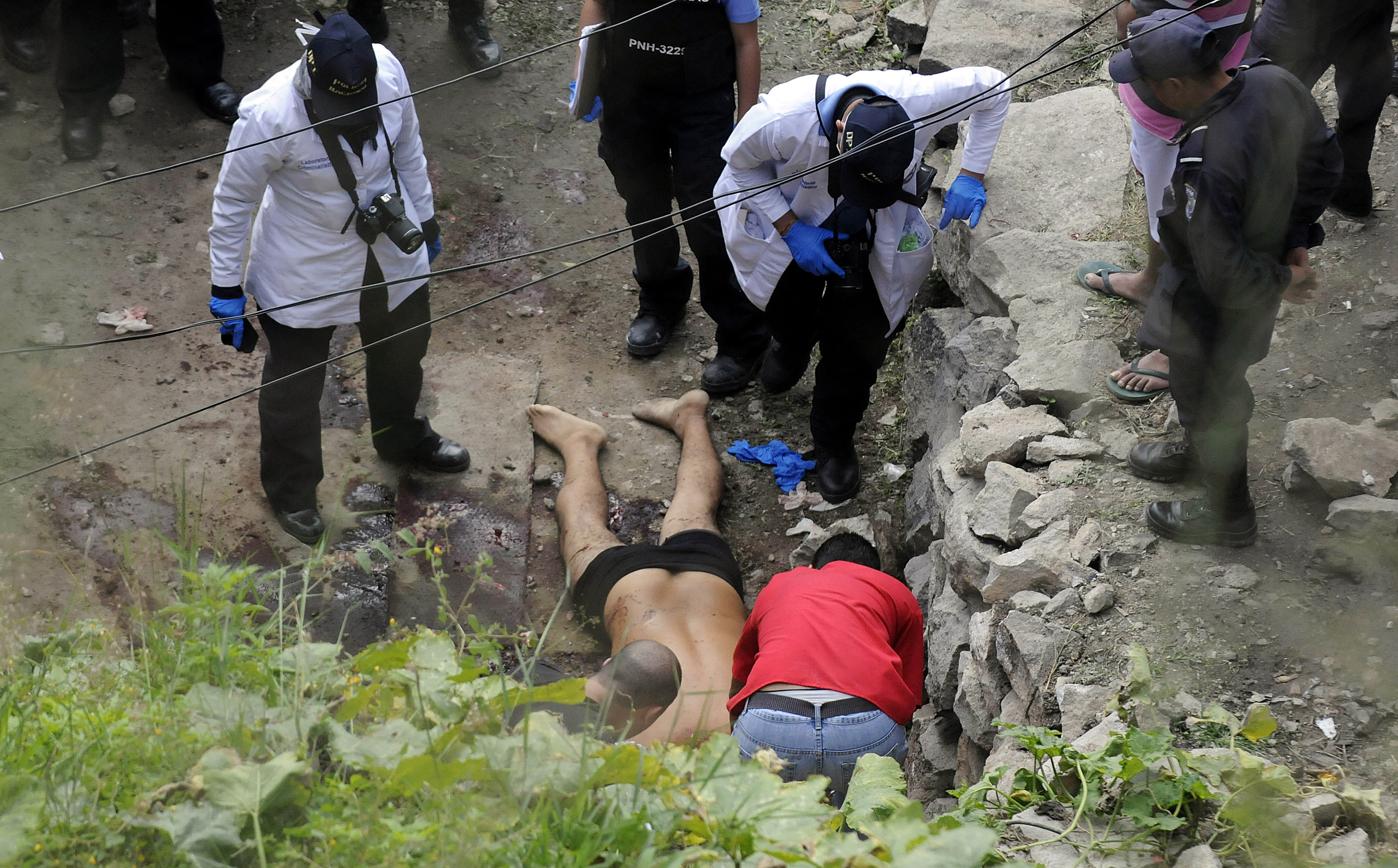 Investigadores recaban evidencia en torno al cuerpo de un hombre que fue asesinado luego que un grupo armado sacó a varias personas de sus viviendas y las ejecutó en un vecindario de Tegucigalpa, Honduras, el miércoles 25 de noviembre de 2015. En Honduras existe desplazamiento interno y externo de población por la violencia y un ambiente de miedo e inseguridad como resultado de las actividades de las pandillas, alertó el relator de ONU para los Derechos Humanos el viernes 27 de noviembre. (AP Photo/Fernando Antonio)