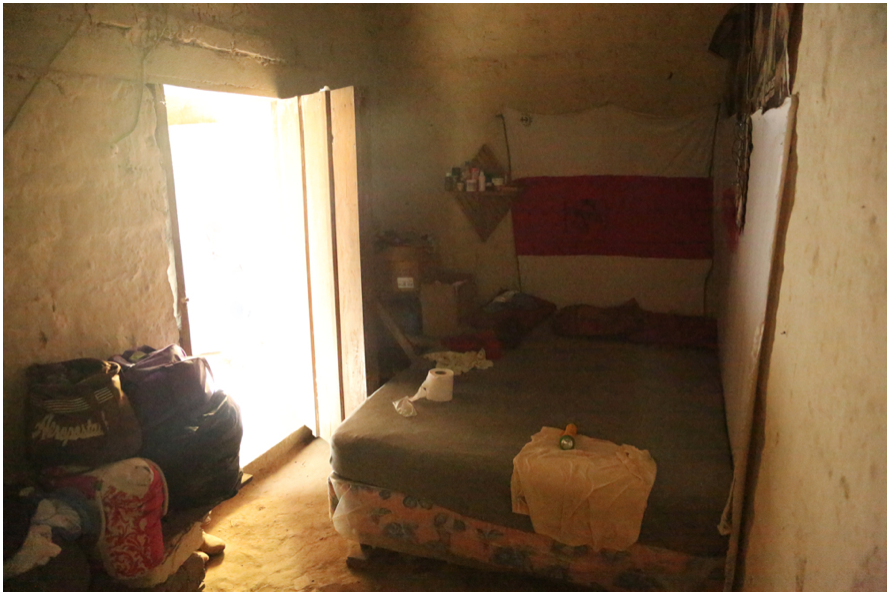 «Acá dormía Berta», recuerda María Santos, una dirigente del COPINH y lideresa de La Tejera, una de las aldeas que conforman la comunidad de Río Blanco. El piso de tierra de la habitación parece una extensión de sus paredes de adobe. Más que un cuarto es un refugio. Apenas cabe una cama y una mesita de noche improvisada con unas tablas carcomidas. Allí descansaba Berta Cáceres cuando les visitaba, expuesta físicamente ante una eventual ejecución extrajudicial, pero amparada bajo la hospitalidad de la comunidad, esa misma que les lleva a compartir sus escasos alimentos a quienes se acercan a escuchar sus testimonios. Fotografía de Dany Barrientos